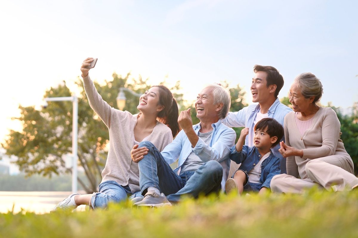 Three generations of a family sitting together on a lawn
